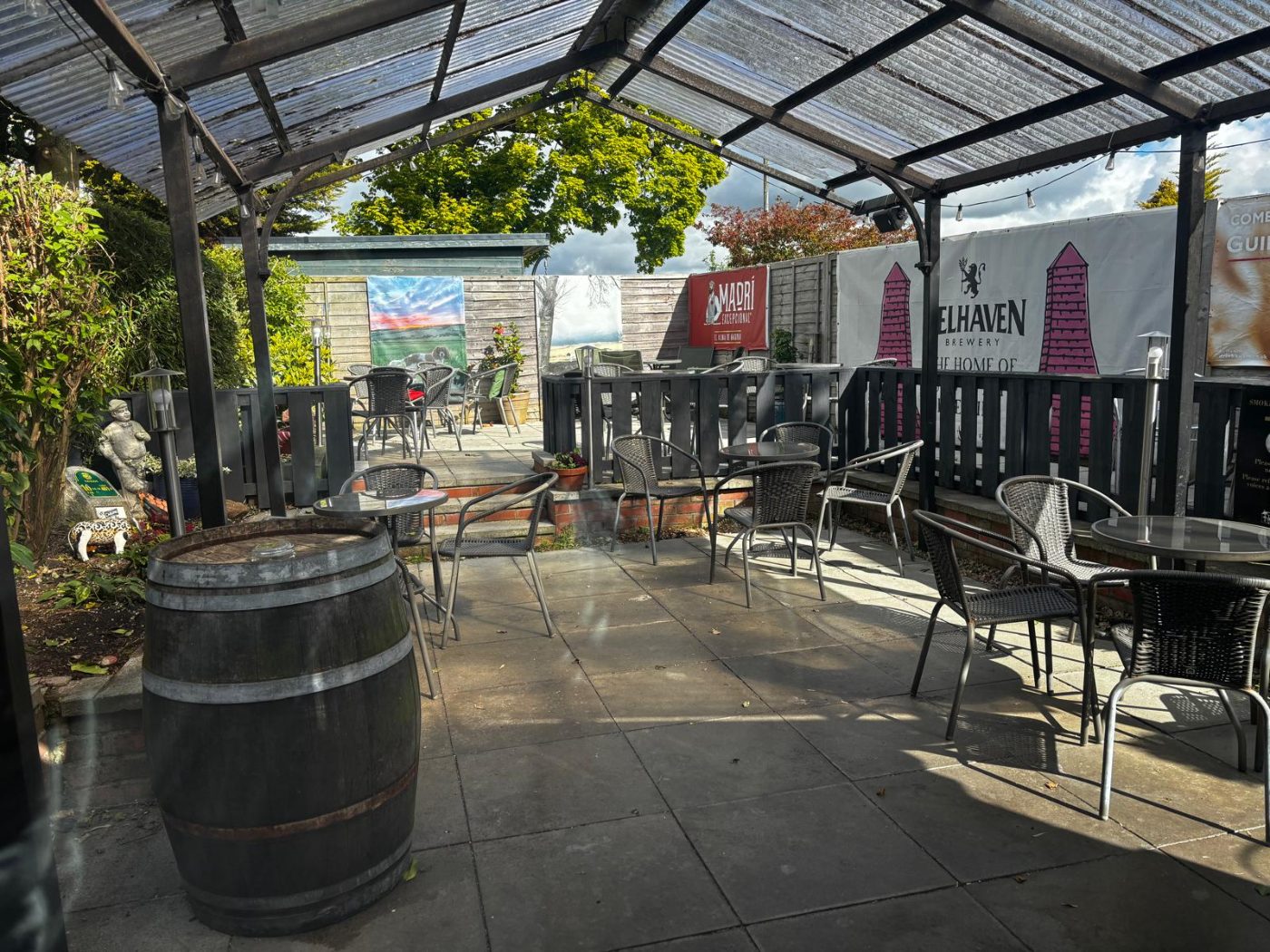 The partially covered beer garden with tables and a barrel