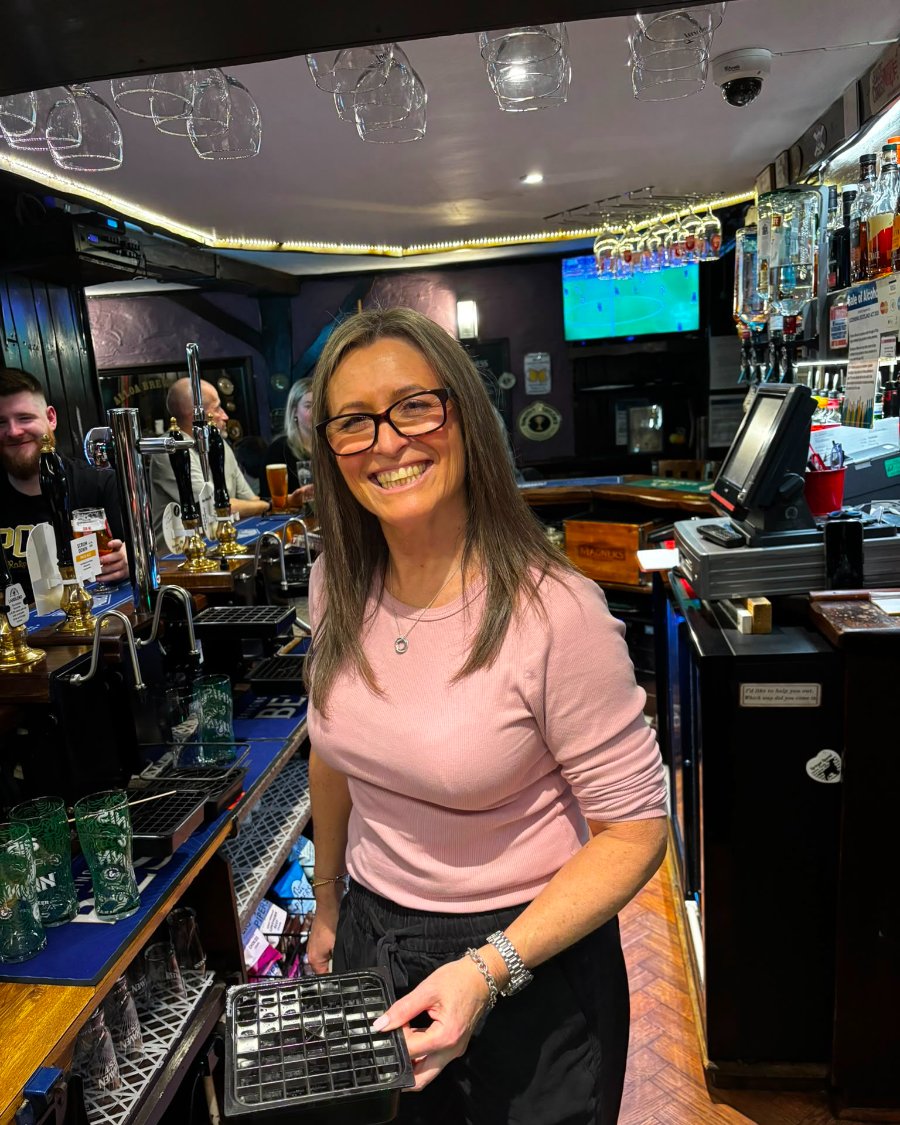 Jo Daley behind the bar collecting glasses
